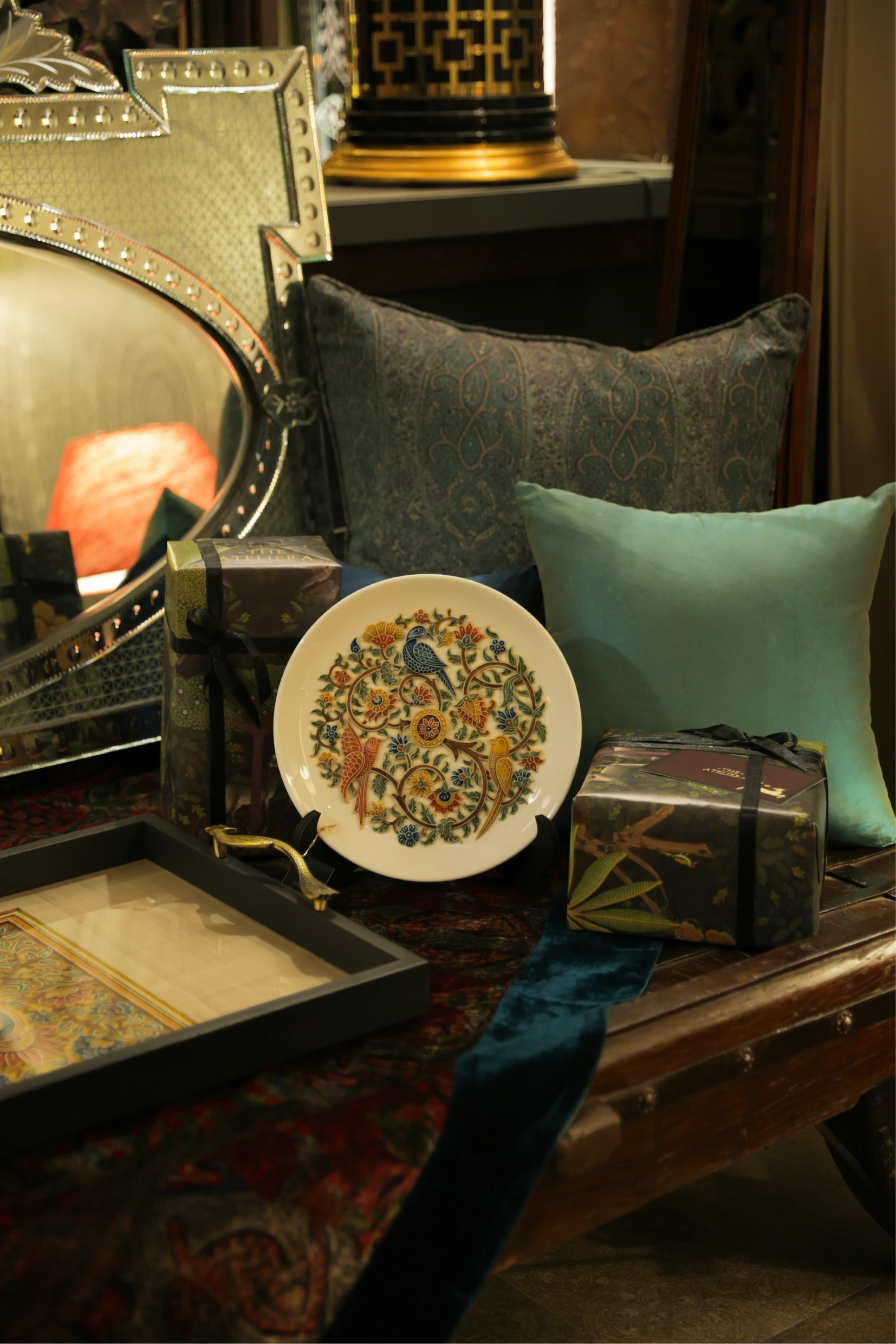 Gallery interior view with warm lighting, framed artwork on walls, and decorative lamp